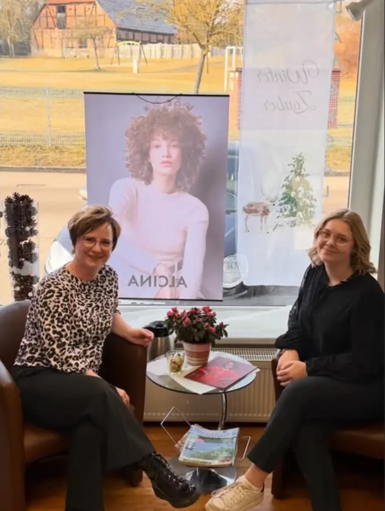 Jana und Lena sitzen im Wartebreich im Salon Gielow und Lächeln in die Kamera